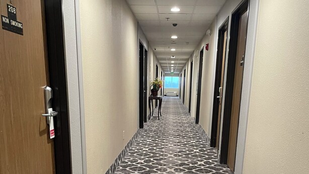 A hotel hallway with a patterned floor, doors on both sides, and a sign indicating a non-smoking area. - Harvest Inn, Dixon/ UC Davis. (Dixon)