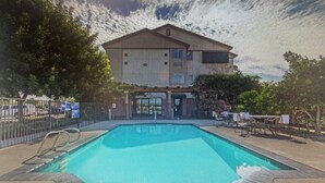 A swimming pool with a fenced area, a building with a flat roof, and a gate. - Harvest Inn, Dixon/ UC Davis. (Dixon)