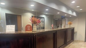 A hotel reception area with a dark wood reception desk, a 'No Pets' sign, and a 'Bloom and Grow' sign. - Harvest Inn, Dixon/ UC Davis. (Dixon)