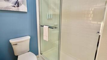 A bathroom with a glass-enclosed shower, a toilet, and a sink.