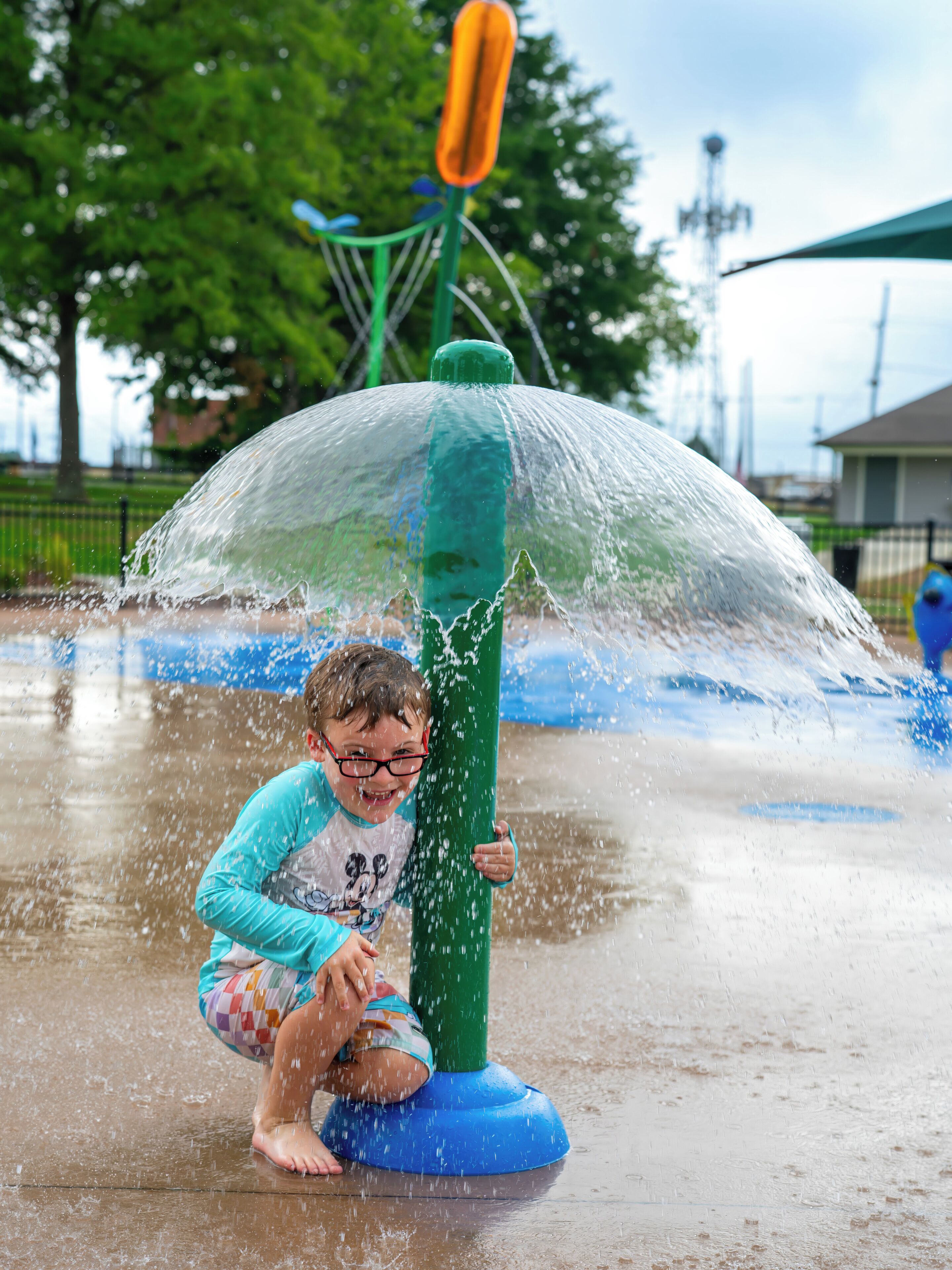 A child playing in a water play area with a transparent dome structure.