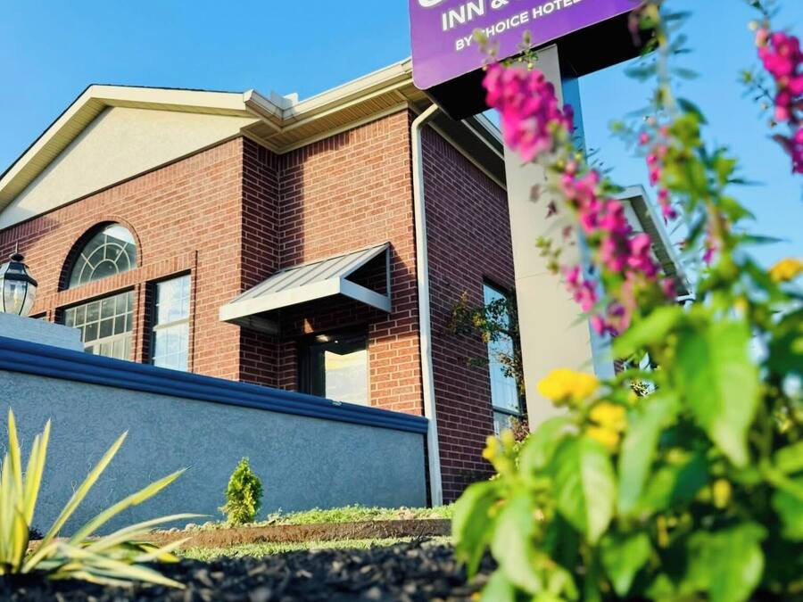 A Sleep Inn & Suites sign with a clear view of the building's brick facade and a well-maintained garden area.