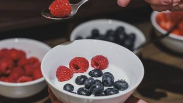 A person holding a bowl with raspberries and blueberries.