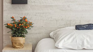 A bedroom with a bed, a bedside table with a lamp, a plant, and a pillow. - Hôtel AKENA Biarritz - Grande plage (Biarritz)