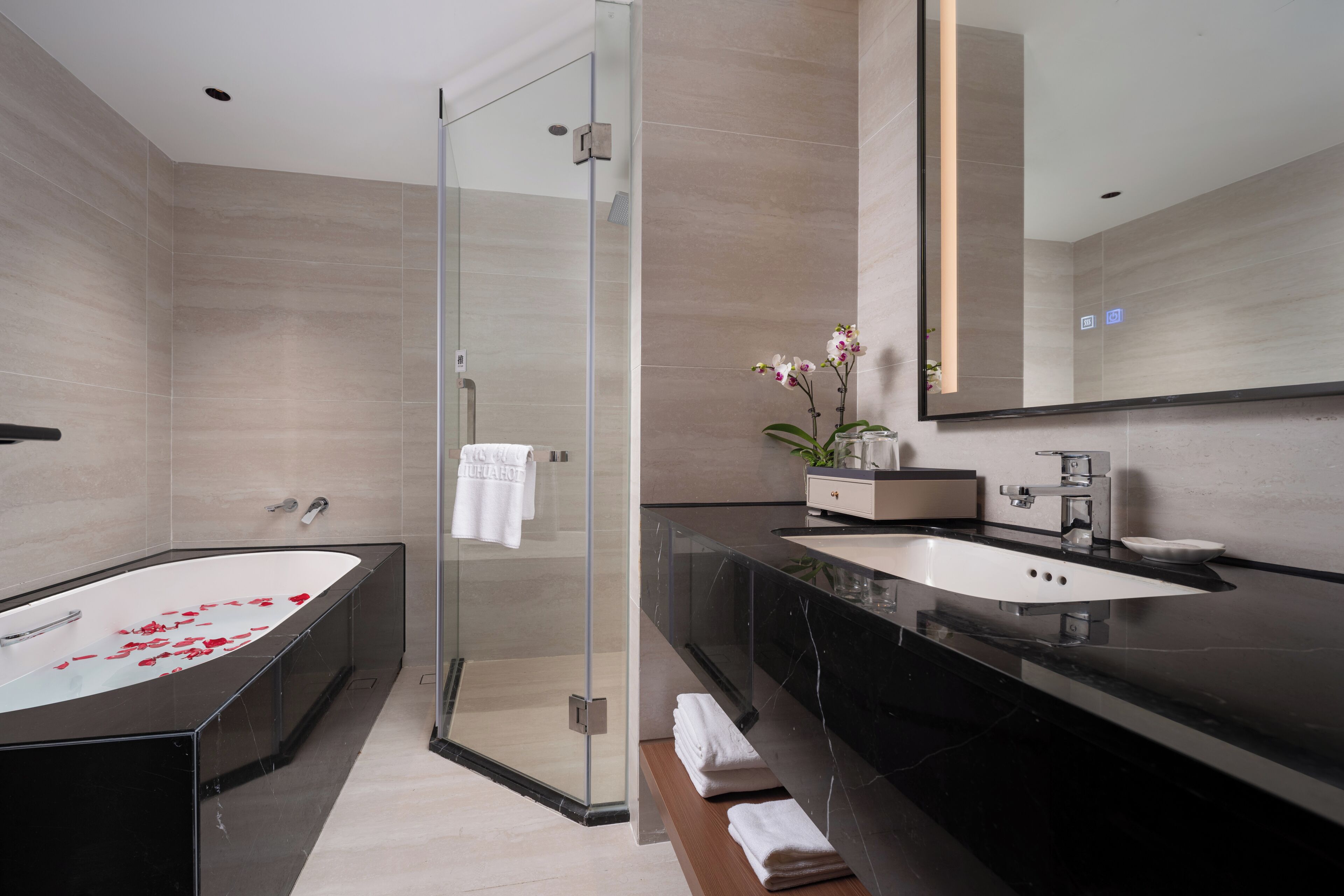 A modern bathroom with a glass-enclosed shower, a freestanding bathtub, and a vanity with a large mirror.