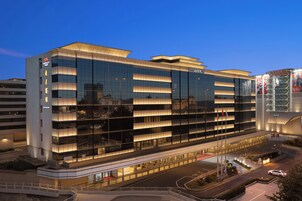 A modern hotel building with multiple floors, large windows, and a well-lit entrance.