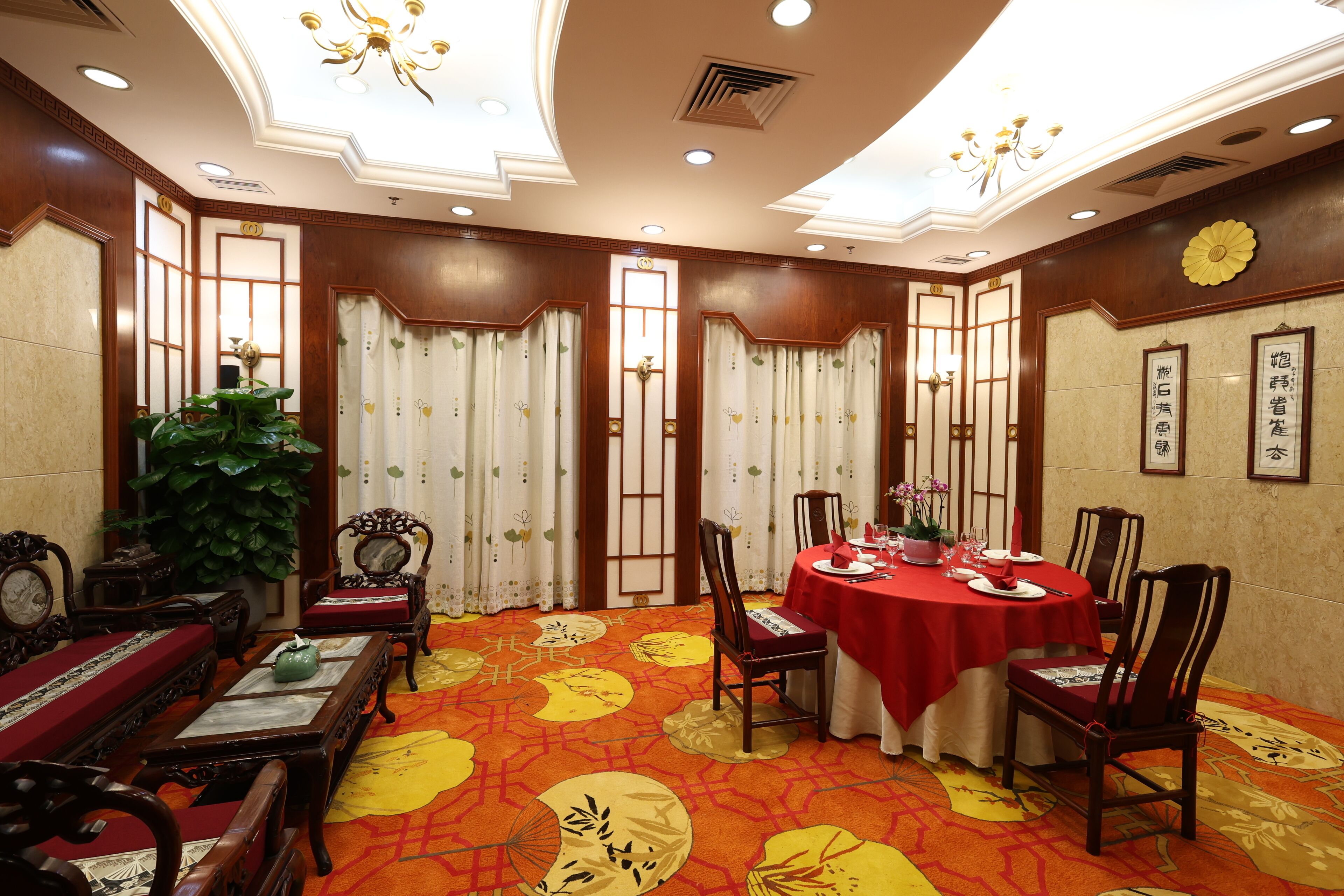 A traditional room with a round table set for dining, wooden furniture, and a patterned carpet.