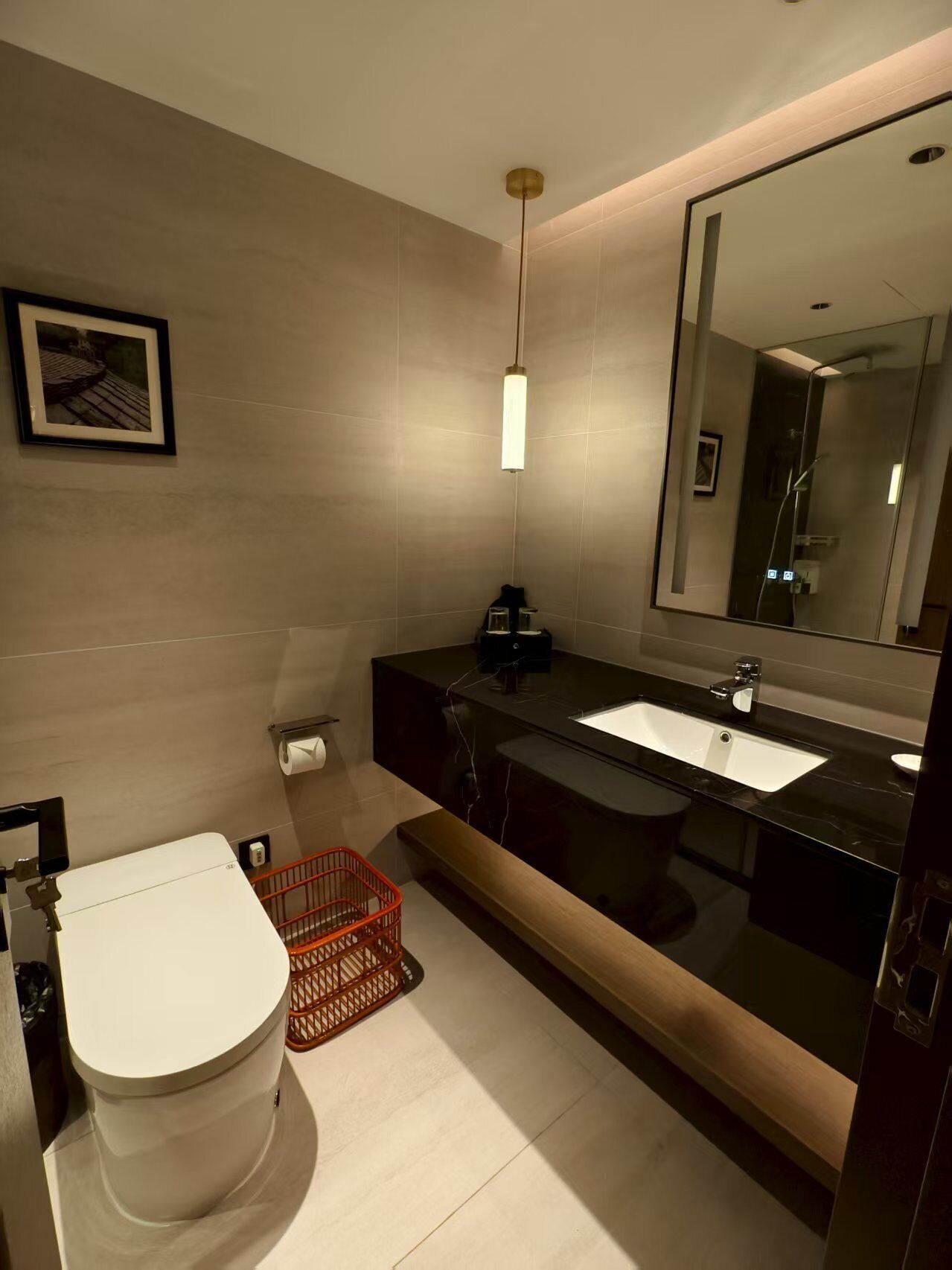 A modern bathroom with a toilet, sink, and mirror.