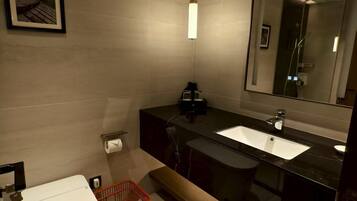 A modern bathroom with a toilet, sink, and mirror.