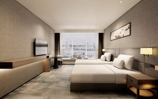 A modern hotel room with a large bed, a TV, a desk, and a view of the city.