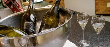 Un tazón metálico con dos botellas de vino y dos copas sobre una encimera.