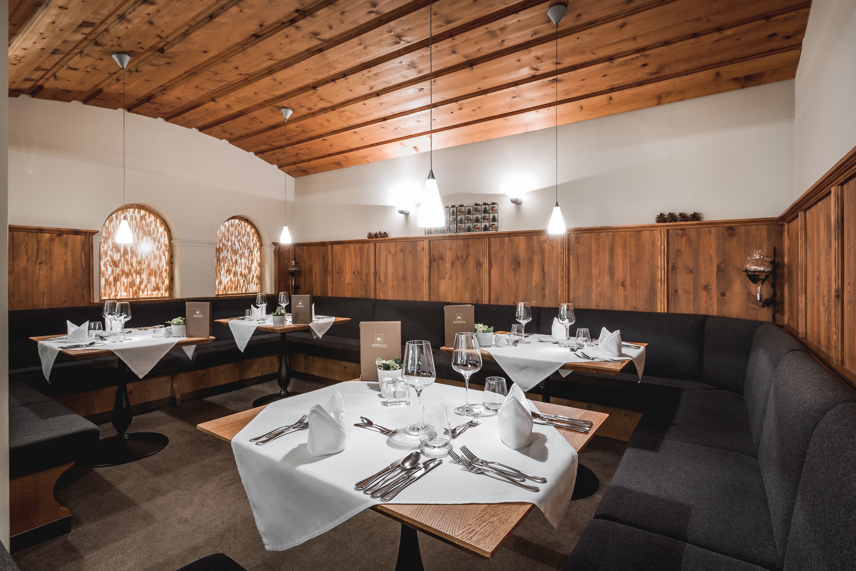 A restaurant with wooden paneling, white tablecloths, and neatly set dining tables.