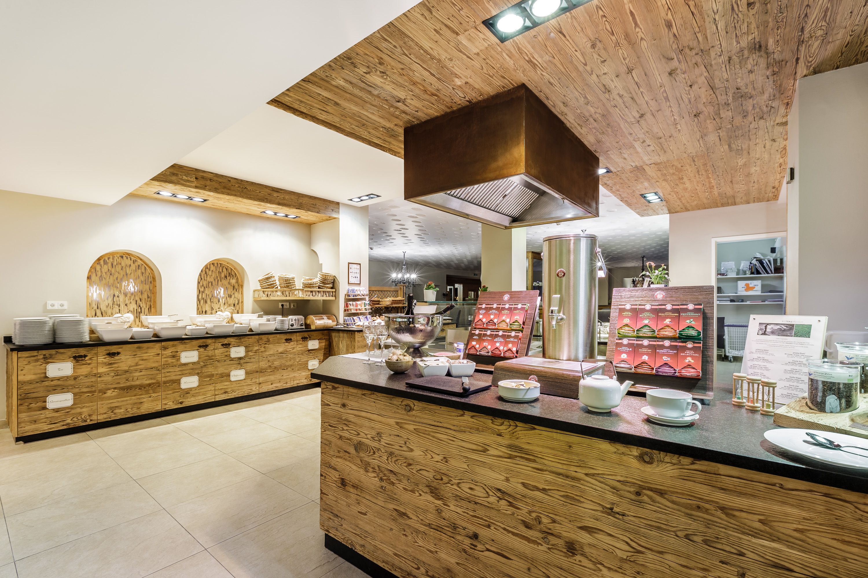Una cocina moderna con muebles de madera, una campana extractora de acero inoxidable y una barra desayunadora con diversos alimentos y utensilios.