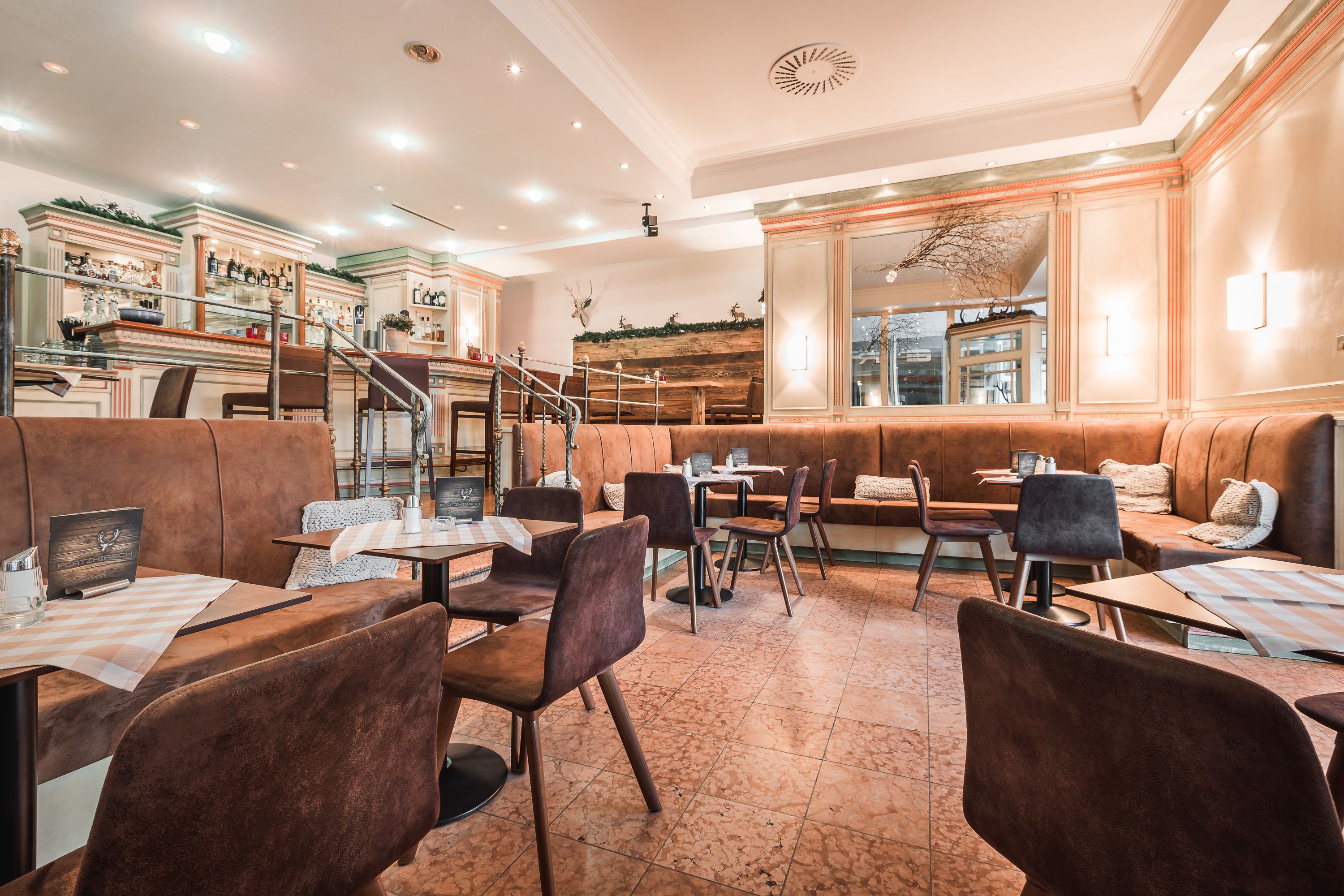 Ein Restaurant mit Sitzgelegenheiten in Form von Boxen und Tischen, einer Bar und einer Treppe zu einer oberen Ebene.