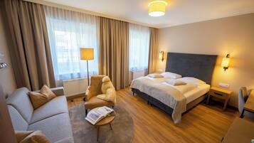 Une chambre d’hôtel comprenant un lit, un canapé, une chaise, une lampe et une table de chevet.