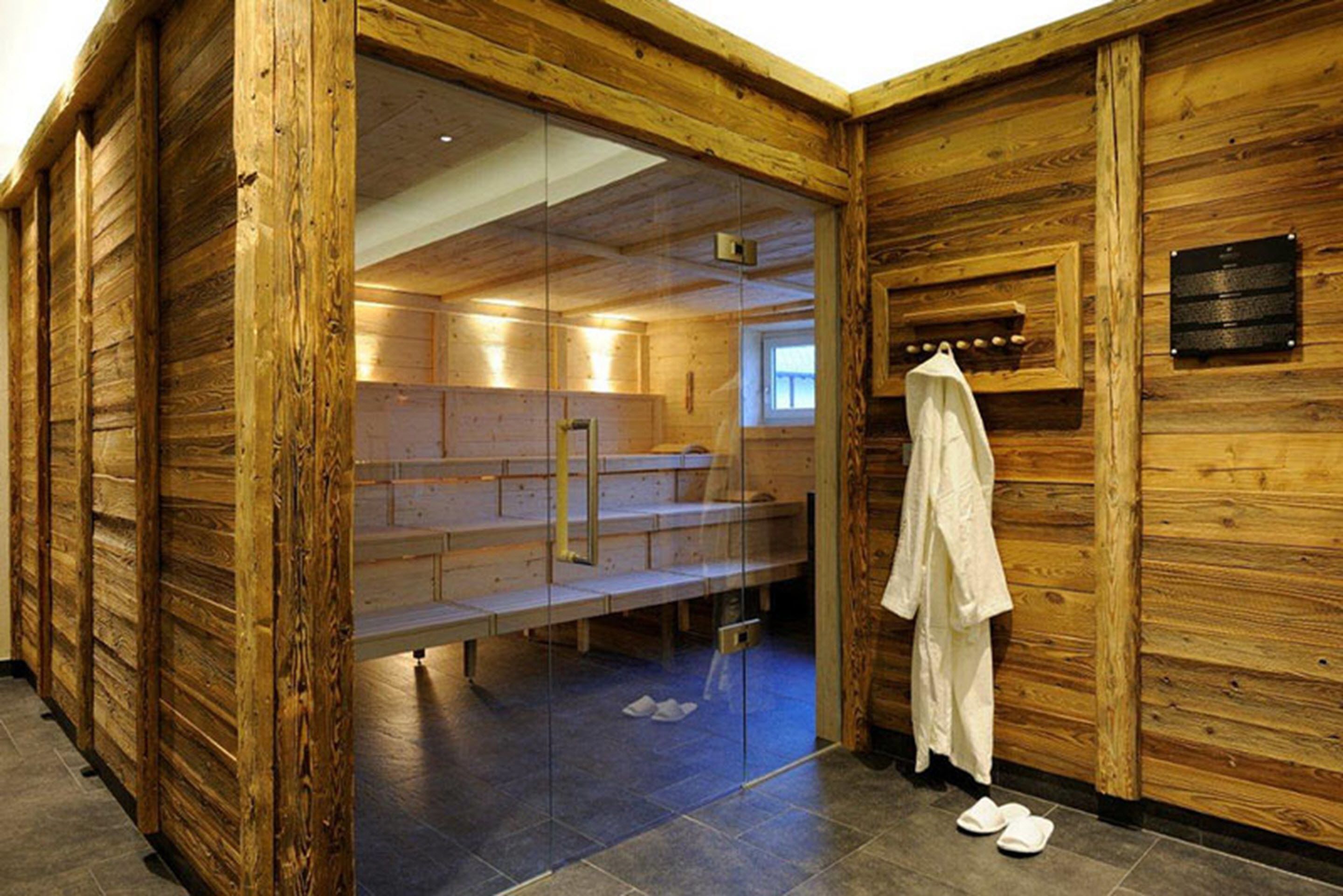 A wooden interior with a bench area, a glass partition, and a towel rack.