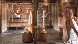 Un sauna con paredes y bancos de madera, puertas de vidrio y piñas decorativas.