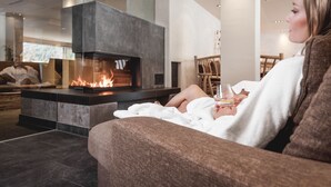 Una sala moderna con chimenea, un sofá y un vaso de bebida.