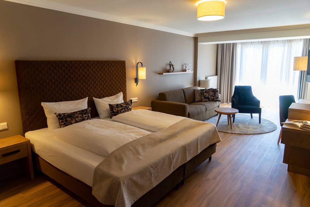 Una habitación de hotel con una cama grande, un sofá, una mesita y una silla.