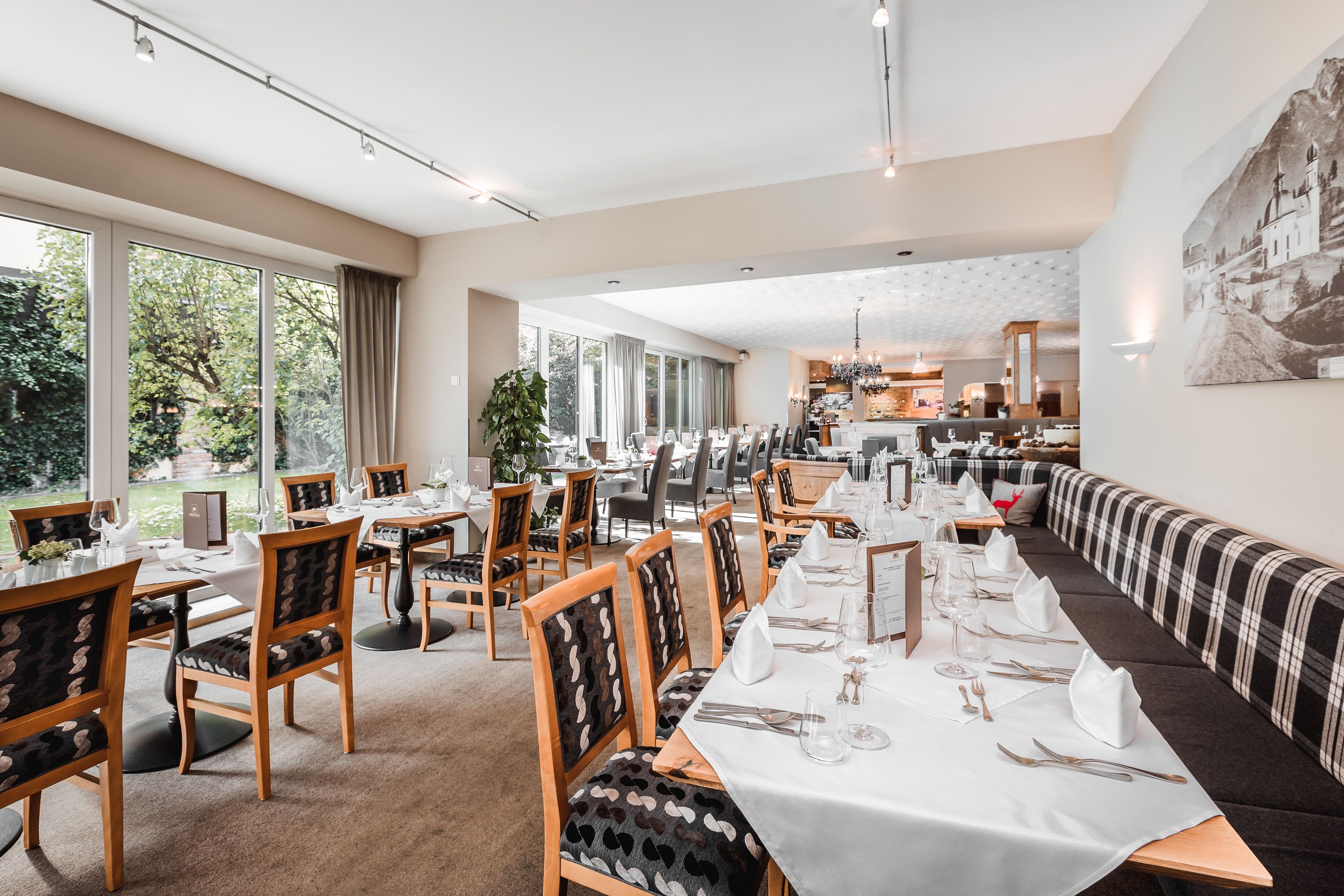 A dining area with long tables, chairs, and a sofa.