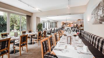 A dining area with long tables, chairs, and a sofa.