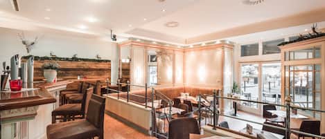 A restaurant with a high ceiling, recessed lighting, and a view of the street through large windows.