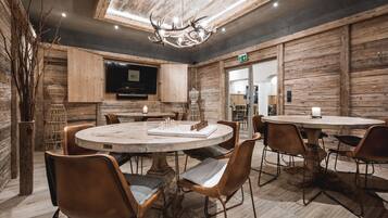 A rustic dining area with wooden walls, a chandelier, and a round table with chairs.