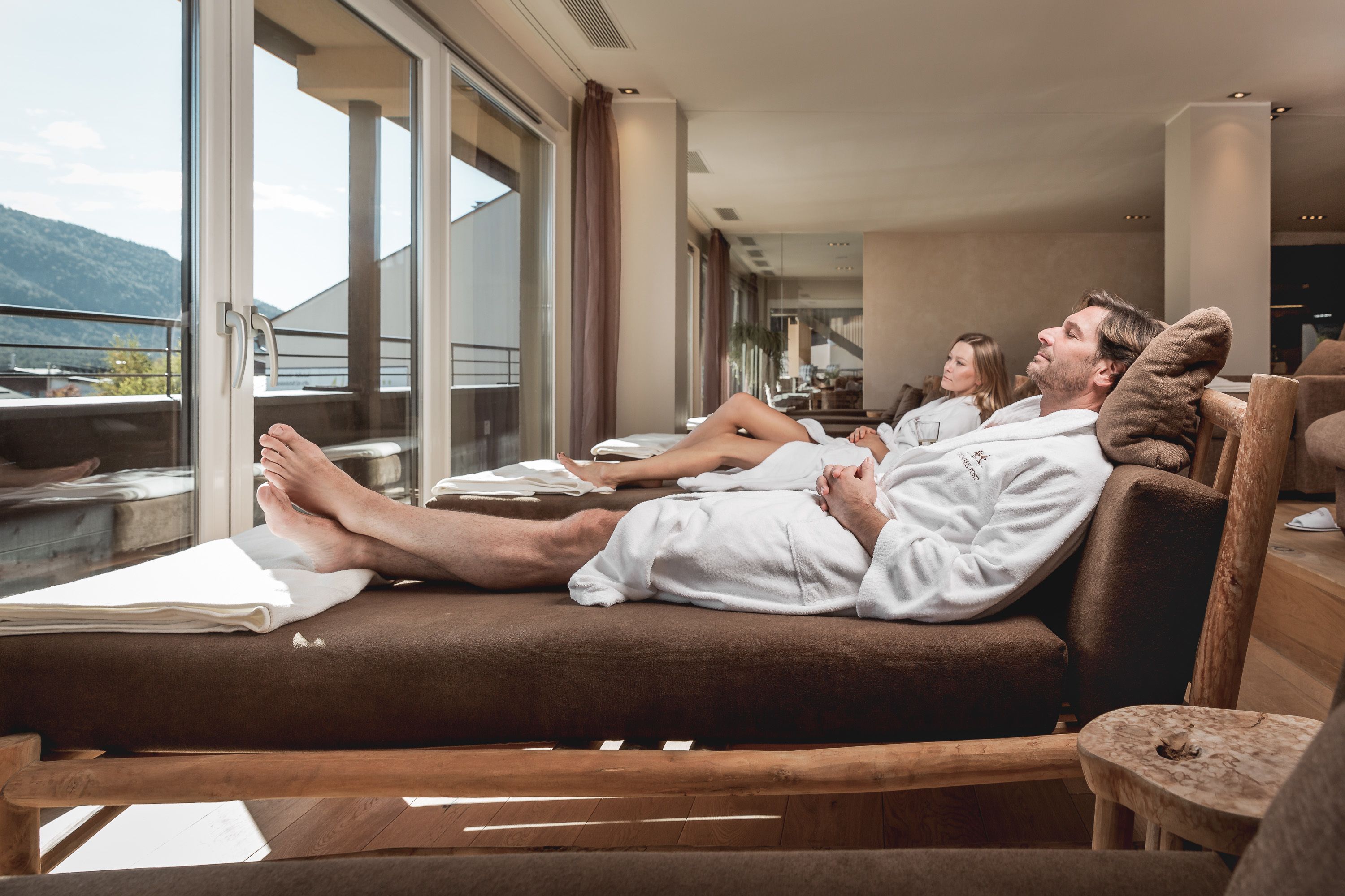 A couple relaxing on a sun lounger with a view of the mountains.