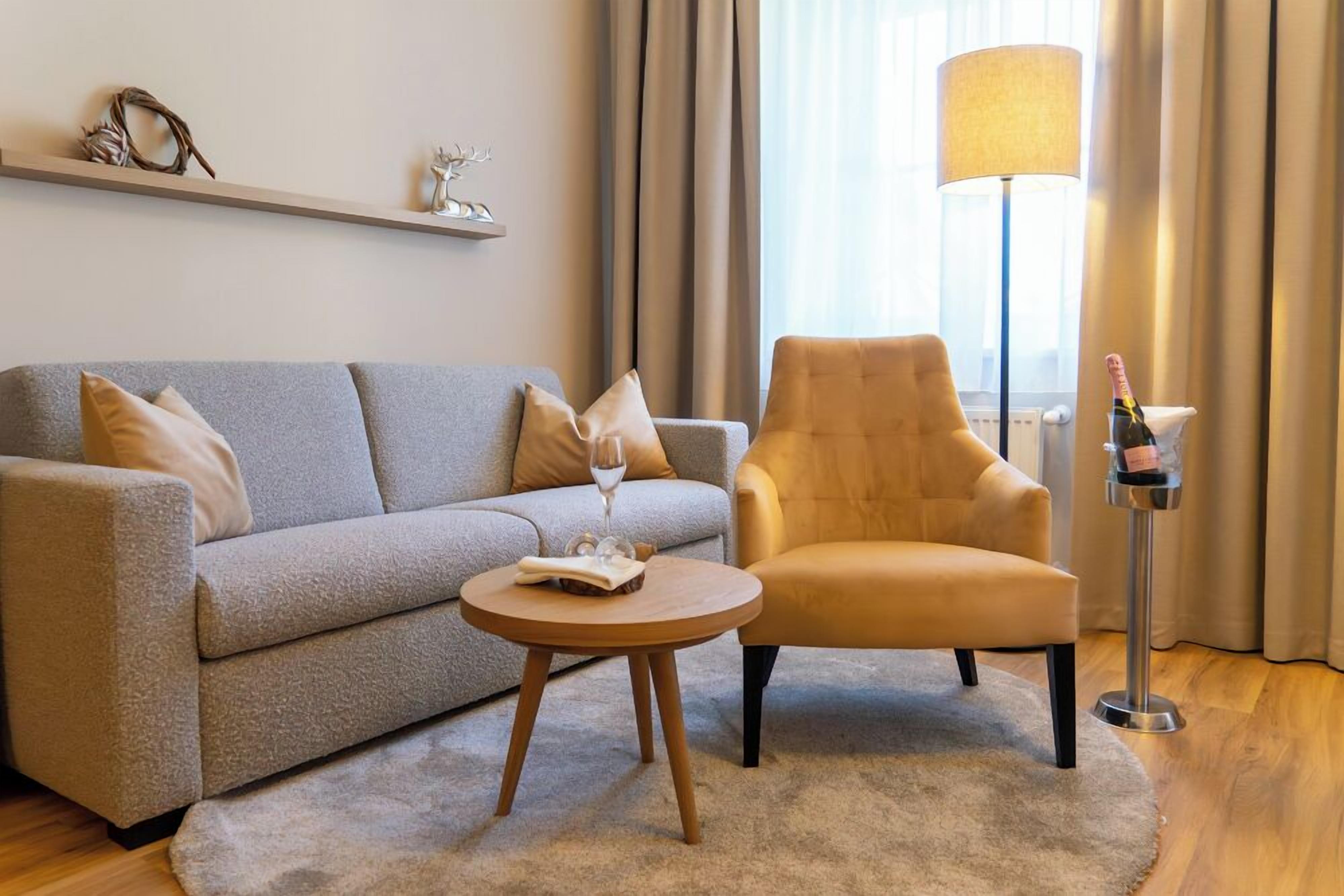 Un salon moderne avec un canapé gris, une table basse ronde en bois, un fauteuil jaune et un lampadaire.