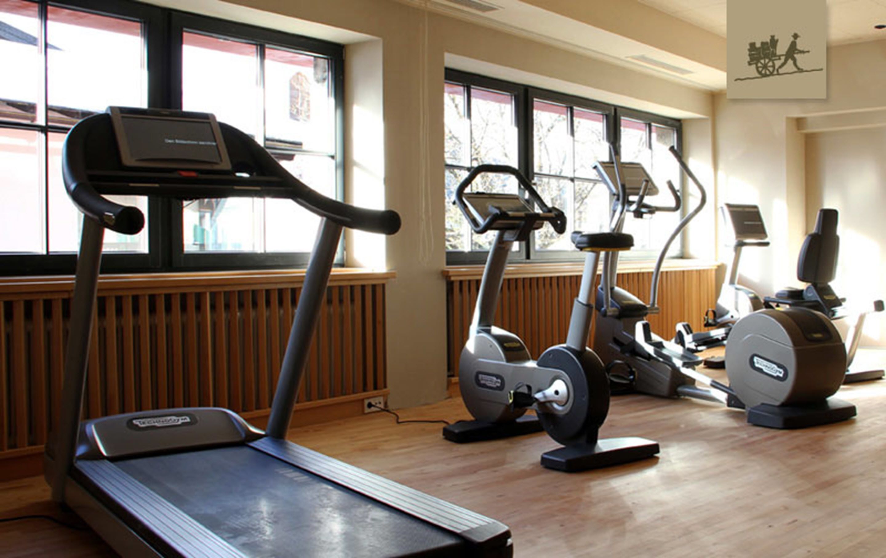 Un gimnasio con cintas de correr, elípticas y una bicicleta estática.