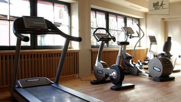 Un gimnasio con cintas de correr, elípticas y una bicicleta estática.