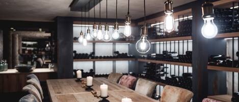 A long wooden table with candles and hanging light bulbs in a modern interior.