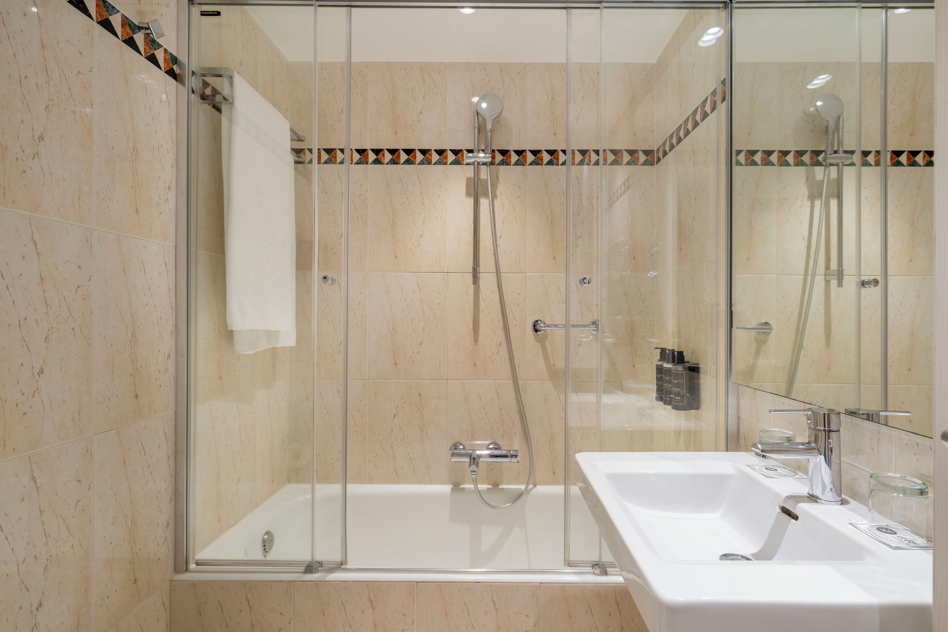 Un baño moderno con ducha de vidrio, una bañera blanca y un lavabo con espejo.