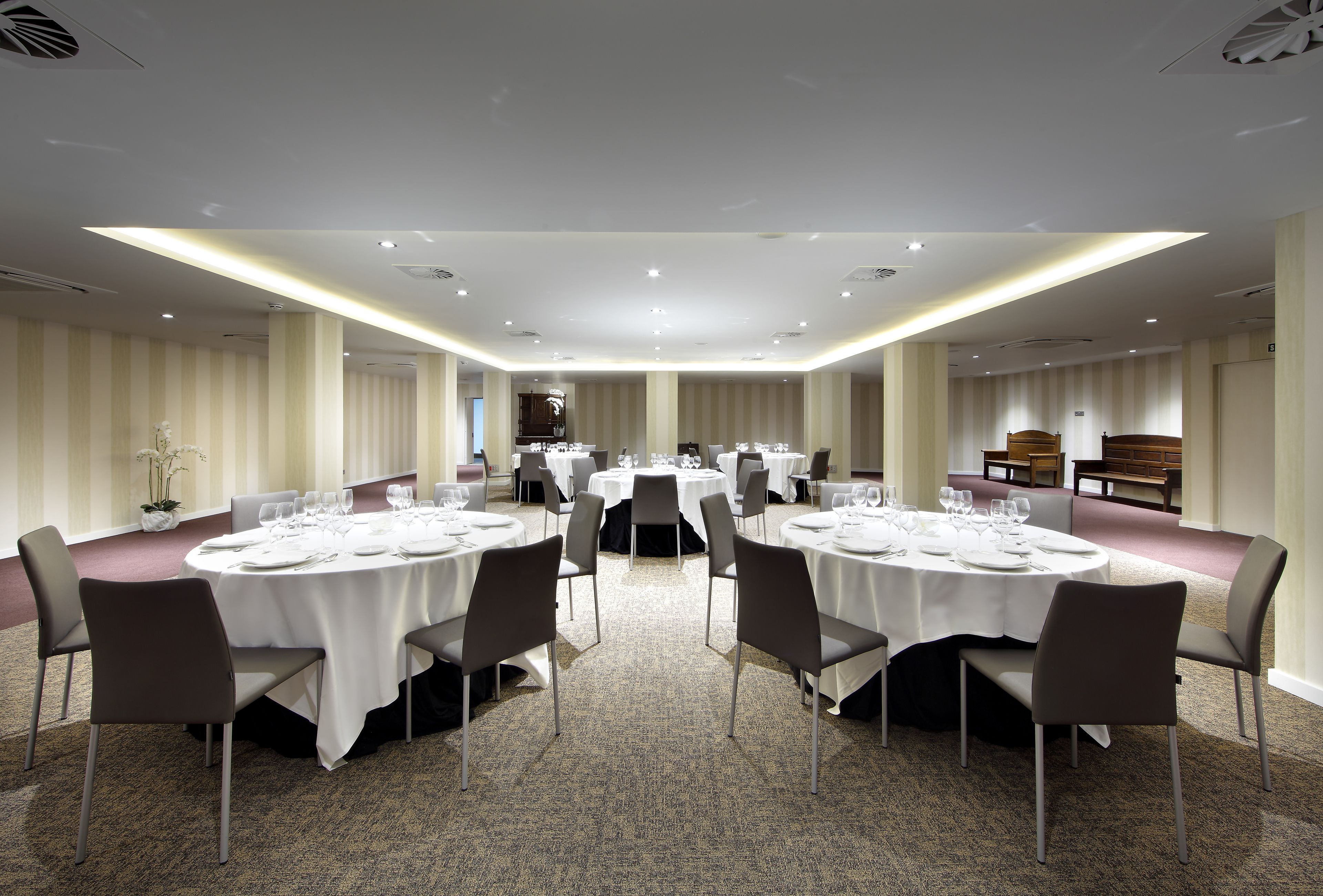 A conference room with round tables, chairs, and a carpeted floor.