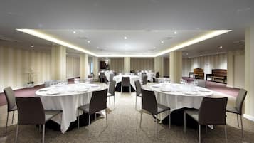 A conference room with round tables, chairs, and a carpeted floor.