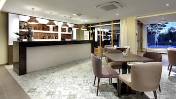 Un comedor moderno con mostrador de recepción, baldosas estampadas y lámparas colgantes.