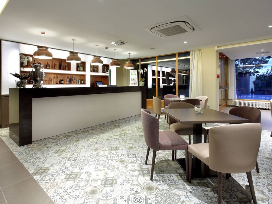 Un comedor moderno con mostrador de recepción, baldosas estampadas y lámparas colgantes.