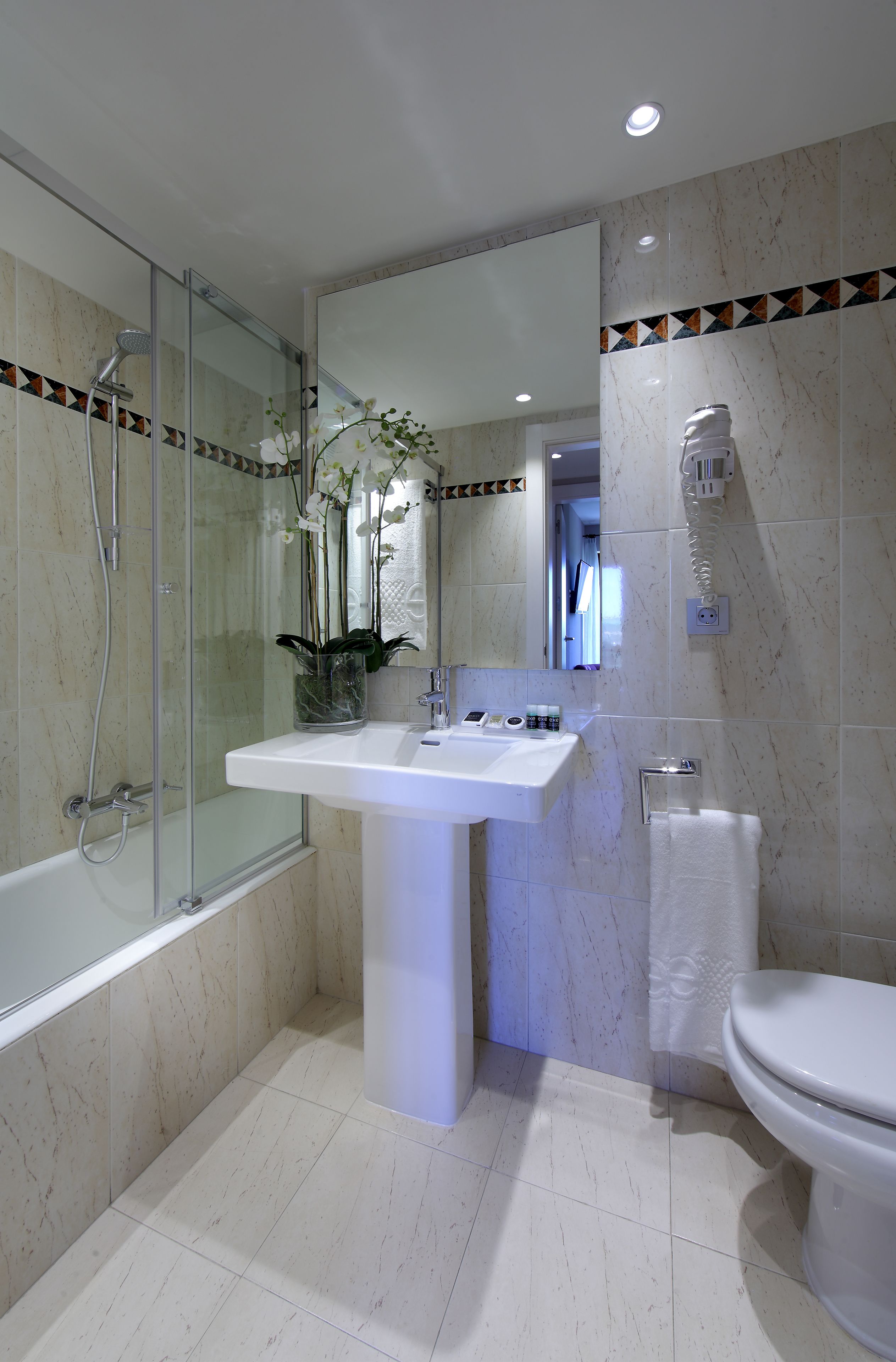 A modern bathroom with a glass-enclosed shower, a white sink, and a toilet.