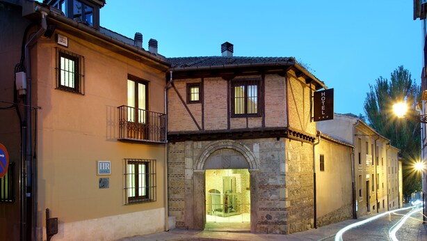 Un edificio histórico con un arco de piedra en la entrada, un balcón y un letrero que indica un hotel.