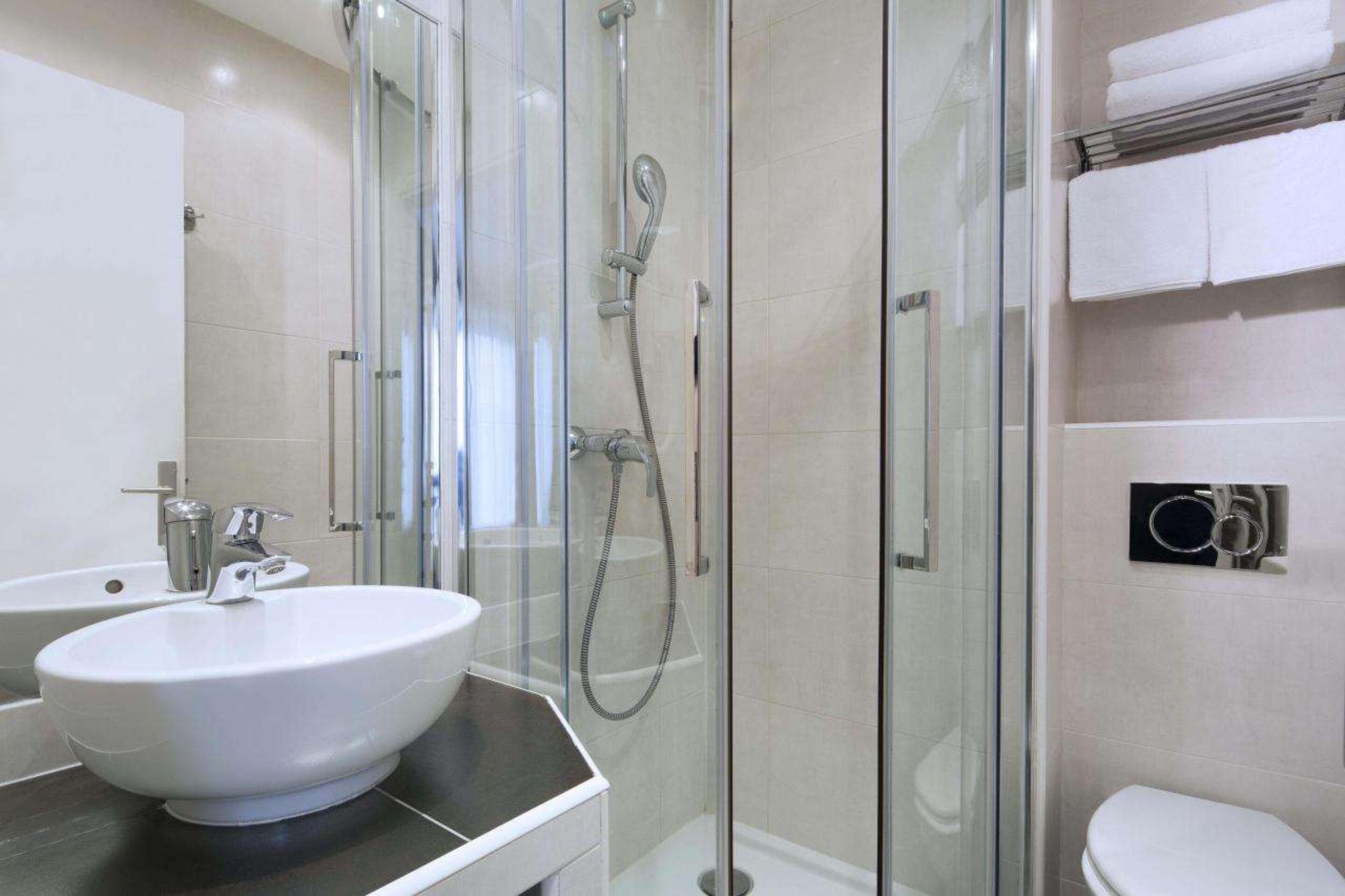 A modern bathroom with a glass-enclosed shower, a white sink, and a toilet.