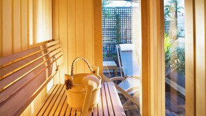 A wooden bench and a wooden bucket with a rope handle in a room with wooden walls and a glass door leading outside. - Le Relais Madeleine (Paris)
