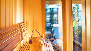 A wooden bench and a wooden table with a woven basket in a room with wooden walls and a view of a garden outside.