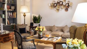A living room with a sofa, armchairs, a coffee table, and a bookshelf. - Le Relais Madeleine (Paris)
