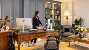 A modern office with a desk, computer, and chair. There is a bookshelf with books and decorative items. - Le Relais Madeleine (Paris)