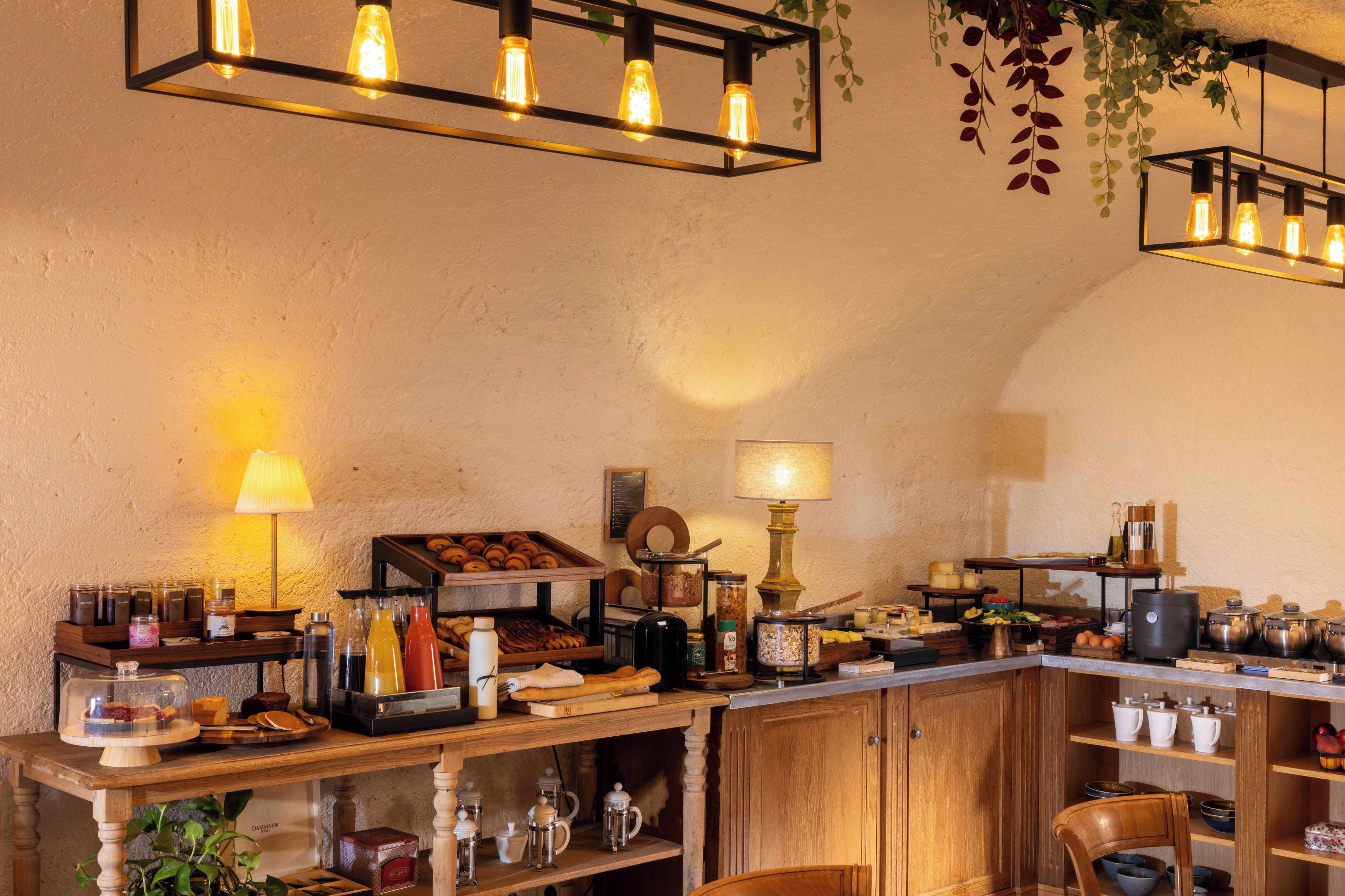 A café interior with a wooden counter, various food items, and hanging light fixtures.