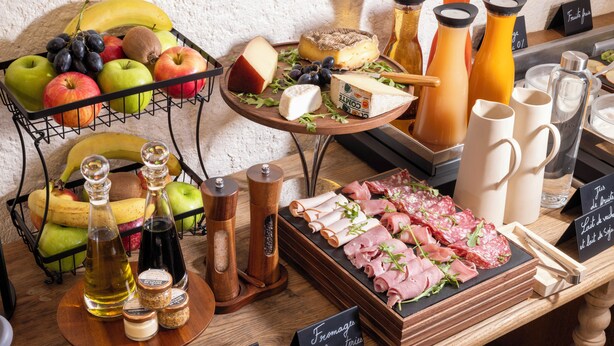 A variety of cheeses, fruits, and condiments on a wooden table. - Le Relais Madeleine (Paris)