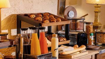 A breakfast buffet with pastries, bread, and beverages.
