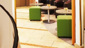 A lobby with leather sofas, green ottomans, and a flat-screen TV on the wall.
