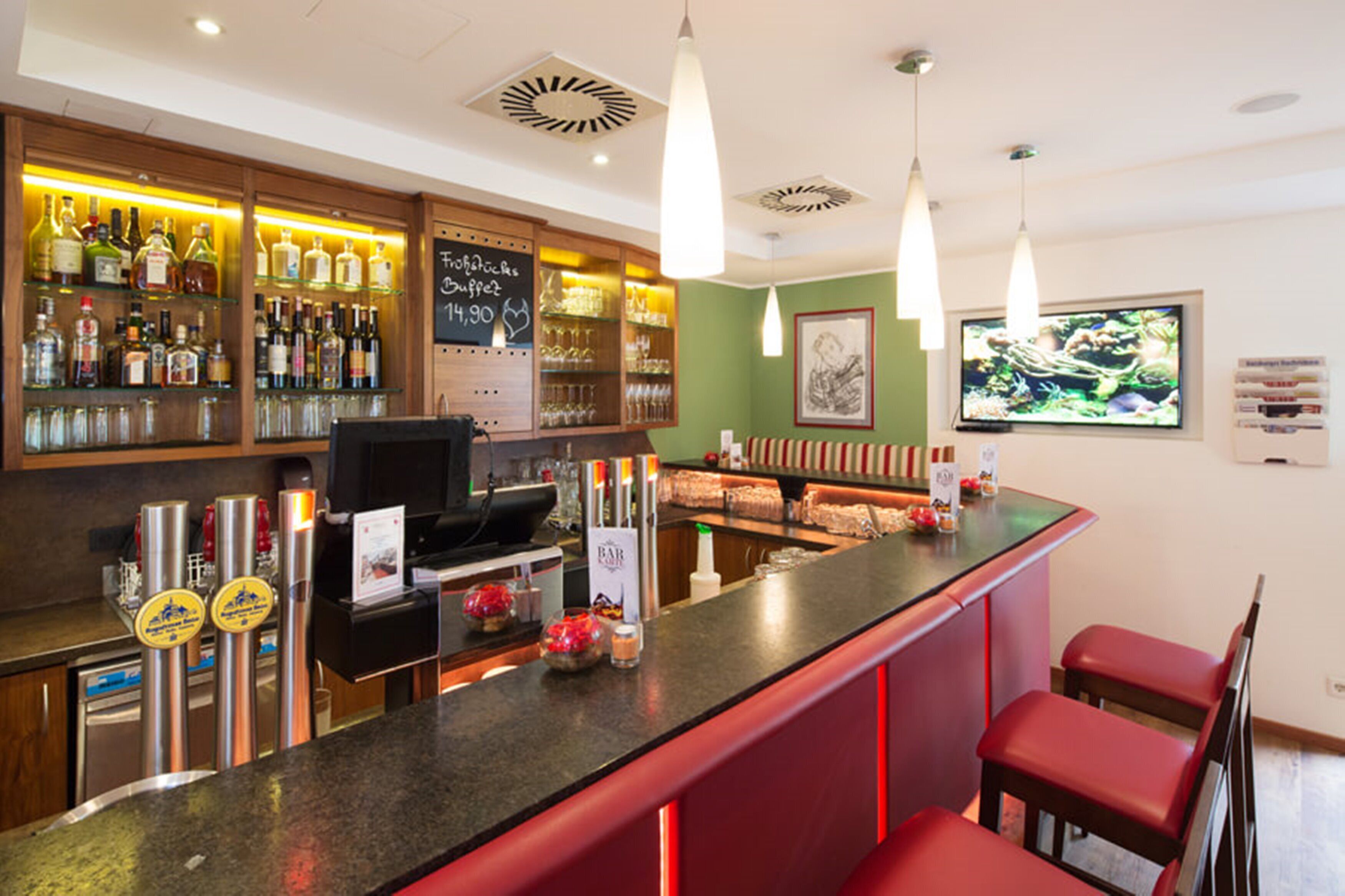 A bar area with a counter, stools, and shelves of bottles.