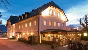 A large, two-story hotel with a well-lit entrance and a covered outdoor seating area.